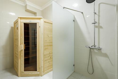 a bathroom with a shower with a wooden cabinet at Bristol Hotel in Krasnodar