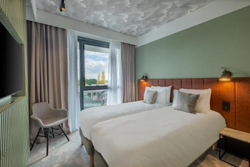 リモネストにあるKYRIAD LYON OUEST Limonestのベッド2台と窓が備わるホテルルームです。