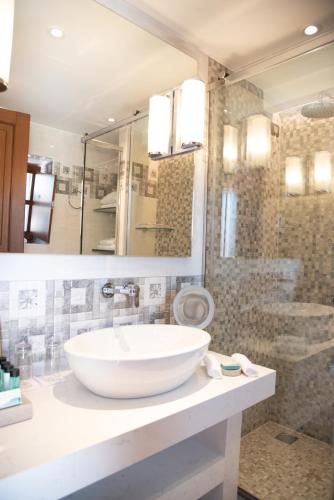 a bathroom with a large white sink and a shower at Mystras Grand Palace Resort & Spa in Mystras