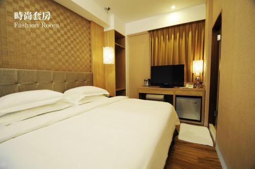 a bedroom with a white bed and a television at The Riverside Hotel Hengchun in Hengchun