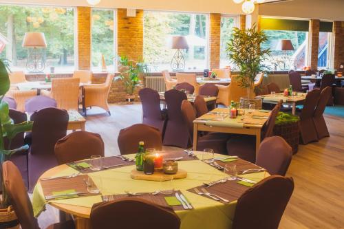 un restaurante con mesas y sillas en una habitación en Hotel de Grote Zwaan, en De Lutte