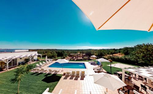 a pool with chairs and umbrellas at a resort at Casa Branca in Tavira