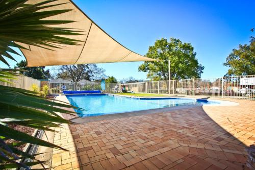 a large swimming pool with a large umbrella at NRMA Dubbo Holiday Park in Dubbo