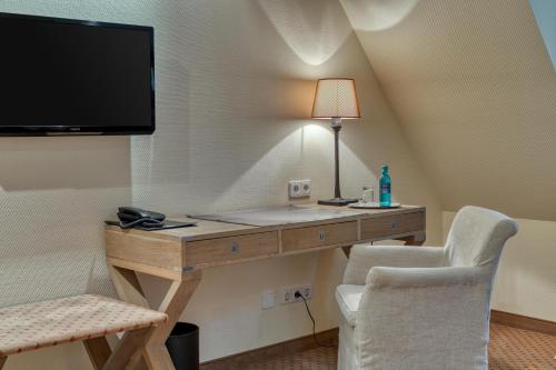 a room with a desk with a tv and two chairs at Hotel Alt Vellern in Beckum