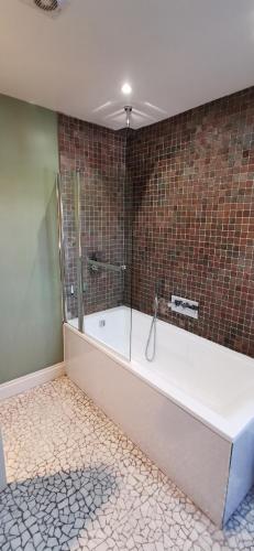 a bathroom with a tub and a tile wall at Buccleuch and Queensberry Arms Hotel in Thornhill