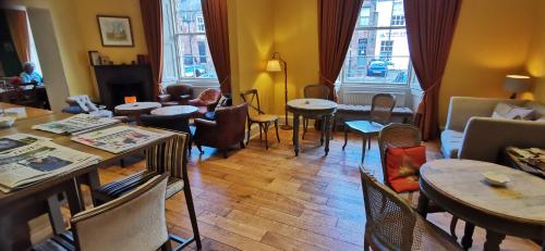 a living room with tables and chairs and windows at Buccleuch and Queensberry Arms Hotel in Thornhill