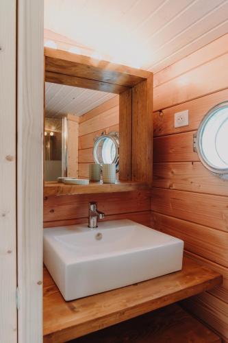 une salle de bain avec un lavabo blanc et un miroir dans l'établissement Les Toues Cabanées du lac, à Le Sauze-du-Lac