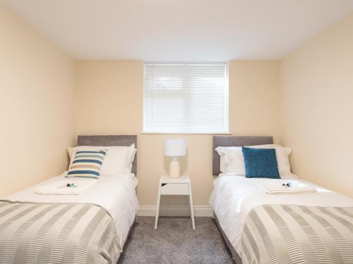 a bedroom with two beds and a chair in it at Dartford Luxurious Apartment in Dartford
