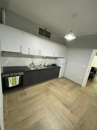 a kitchen with white cabinets and a wooden floor at Eagle’s Nest in Shkodër