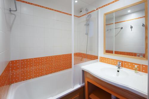 a bathroom with a sink and a tub and a mirror at Résidence Pierre & Vacances la Corniche de la Plage in Bénodet
