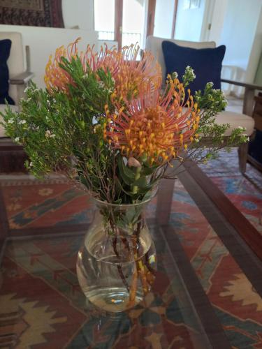 a glass vase with flowers on a table at Barton Luxury Villas in Botrivier