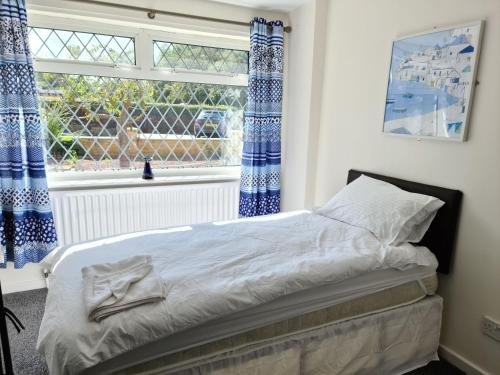 a bedroom with a bed with blue curtains and a window at Warsett Crescent, 5 bedrooms near the coast. in Skelton