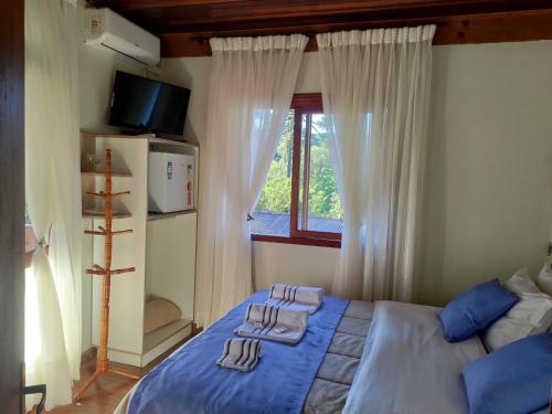 a bedroom with a bed with blue sheets and a window at Pousada Unser Haus in São Francisco de Paula