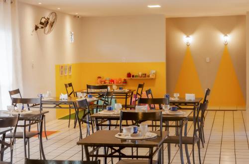 a dining room with tables and chairs and yellow walls at Pousada Serra Bella in Tianguá