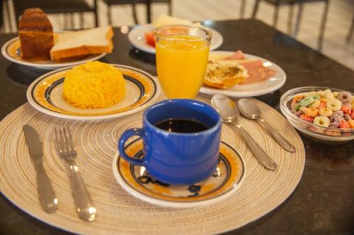 - une table avec des assiettes de nourriture et une tasse de jus d'orange dans l'établissement Pousada Serra Bella, à Tianguá
