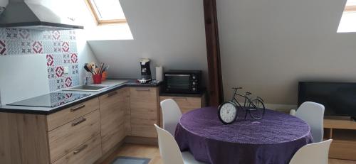 een keuken met een paarse tafel met stoelen en een aanrecht bij Le Maréchal in Gien