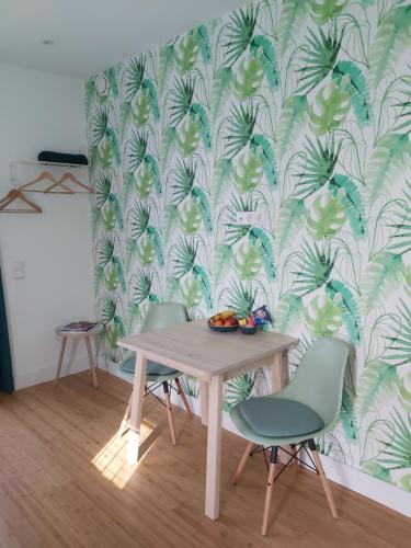 einen Esstisch und Stühle mit einer tropischen Tapete in der Unterkunft Luxury Suites Oosterwold in Almere