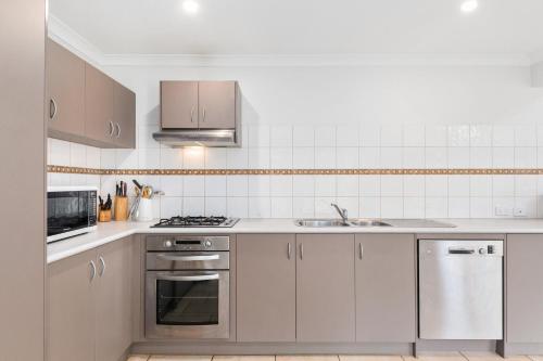 a kitchen with white cabinets and stainless steel appliances at Kangaroo Retreat - Family Favourite Bush Retreat with Kangaroos in Margaret River in Margaret River Town