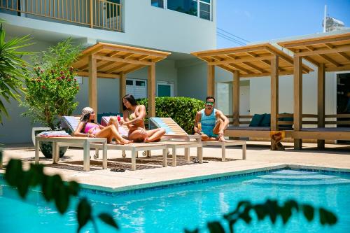 a group of people sitting on benches next to a swimming pool at Numero Uno Piñones in Loiza