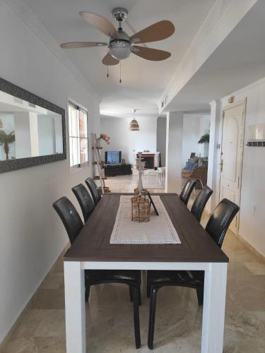 a dining room table with chairs and a ceiling fan at Center beach 2 beds Appartement Elviria in Marbella