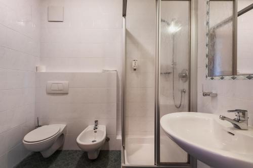 a bathroom with a toilet and a sink and a shower at Margun - Apartments & PanoramaRooms in Malles Venosta