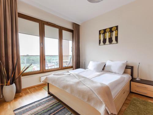 a bedroom with a bed and a large window at VacationClub - Olympic Park Apartament C602 in Kołobrzeg