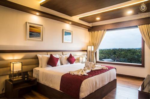 a bedroom with a bed and a large window at KPM TRIPENTA HOTEL in Kozhikode