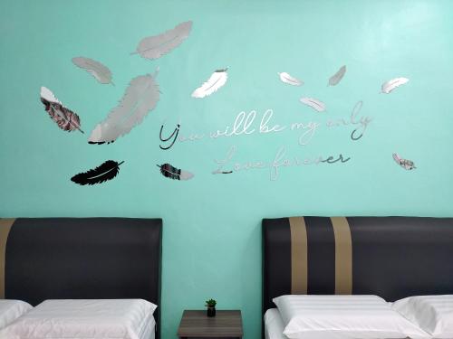 a bedroom with two beds with feathers on the wall at U&I HOMESTAY KAMPAR in Kampar