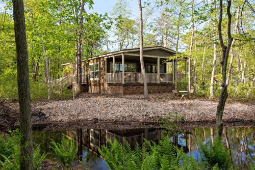 a house in the woods with a reflection in the water at Swan Lake Resort in Galloway