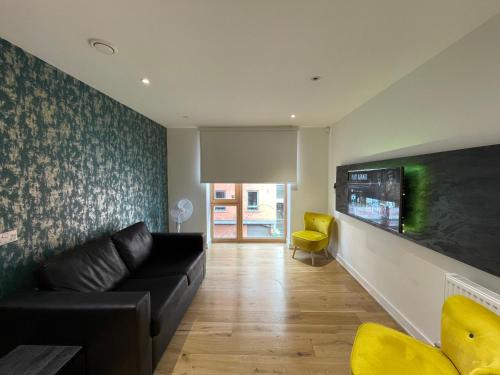 a living room with a black couch and a yellow chair at Quay Apartments Manchester in Manchester