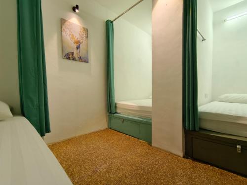 a bedroom with green curtains and a mirror and a bed at Beds In Garden Hostel in Ipoh
