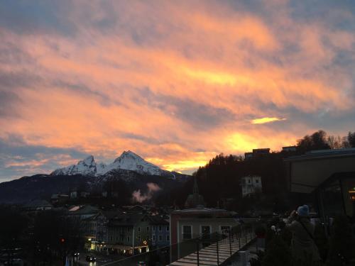 a sunset over a city with a snow covered mountain at Ferienwohnung Gouiaa in Bischofswiesen