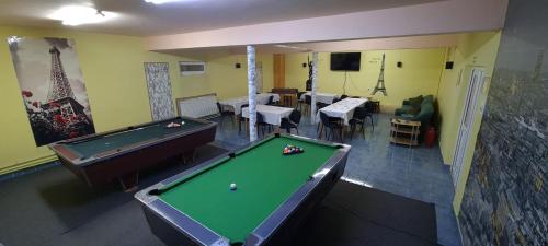 a room with a pool table and tables and chairs at Pensiunea Aurora -Hostel Voineasa in Voineasa