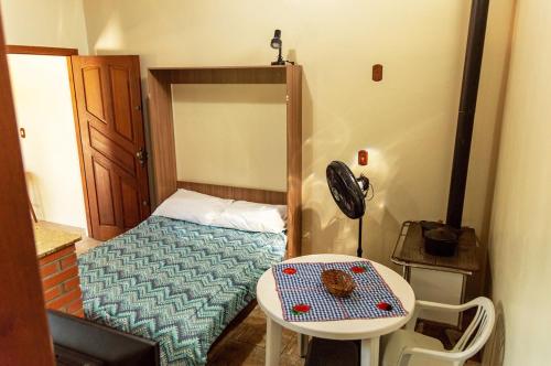 a small bedroom with a bed and a table at Chale c piscina e churrasqueira em Sao Leopoldo-RS in São Leopoldo