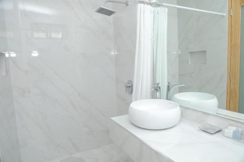 a white bathroom with a sink and a shower at Kaleo Hotel Boutique in San Salvador