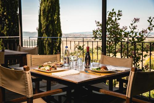 una mesa de madera con comida y bebida en el balcón en A440 in Tuscany, en Pienza