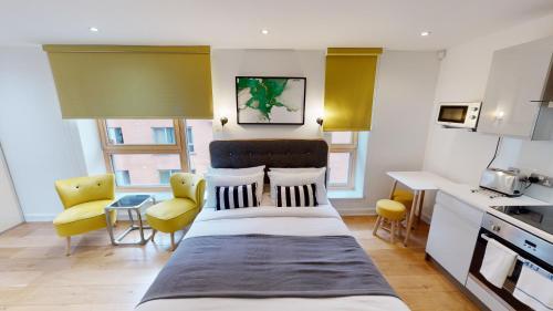 a bedroom with a large bed and yellow chairs at Quay Apartments Manchester in Manchester