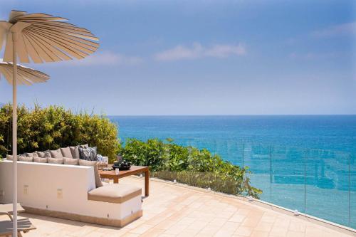 内尔哈Horizonte Club in Nerja by Solaga Holiday Homes的一个带桌子和遮阳伞的庭院和大海