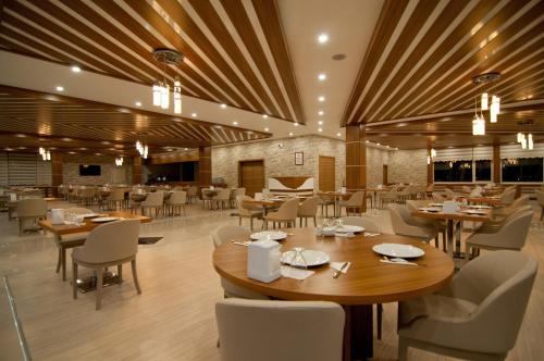 un restaurante con techos de madera, mesas y sillas en Mus Grand Hotel, en Muş