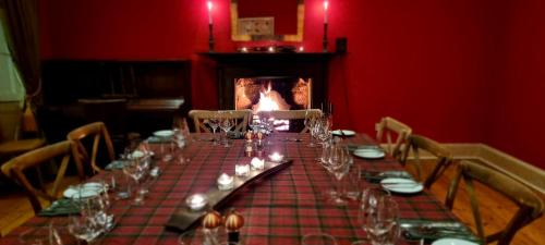 a long table with wine glasses and a fireplace at Buccleuch and Queensberry Arms Hotel in Thornhill