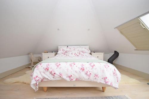 a white bedroom with a bed with pink flowers at The Barn at Guiles , Petersfield in Petersfield