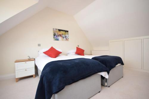 a bedroom with two beds with red pillows at Tabernacle Cottage, Birdham in Birdham