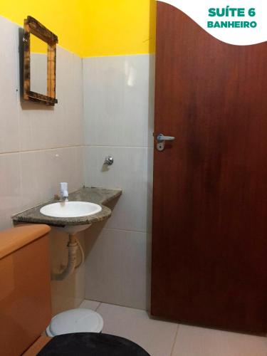 a bathroom with a sink and a wooden door at Suítes do Pontal in Arraial do Cabo