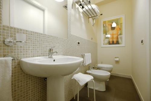 uma casa de banho branca com um lavatório e um WC em B&B Le Sorelle em San Leone