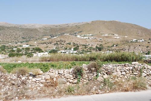 a stone wall with a mountain in the background at Siroco's Rooms And Studios in Parikia