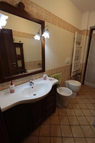 een badkamer met een wastafel, een toilet en een spiegel bij Casa Riva in Terni