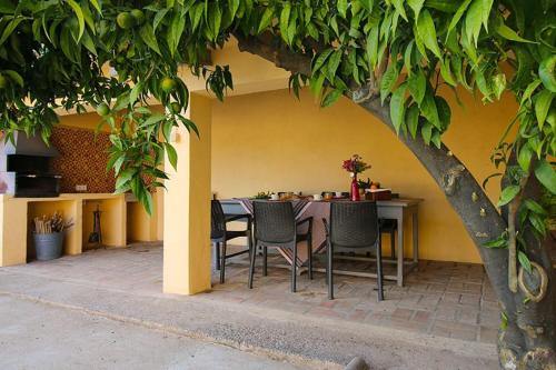 un patio con mesa, sillas y un árbol en Casa TAPIOLAS, en Borrassá