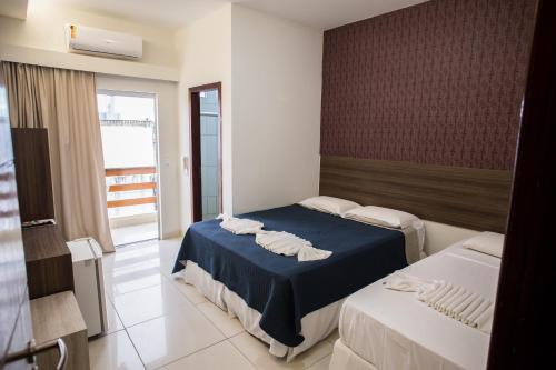 a hotel room with two beds and a window at Pousada Orla dos Corais in Maragogi