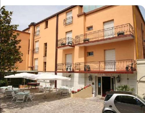 a building with tables and umbrellas in front of it at Hotel Riposo in Gatteo a Mare