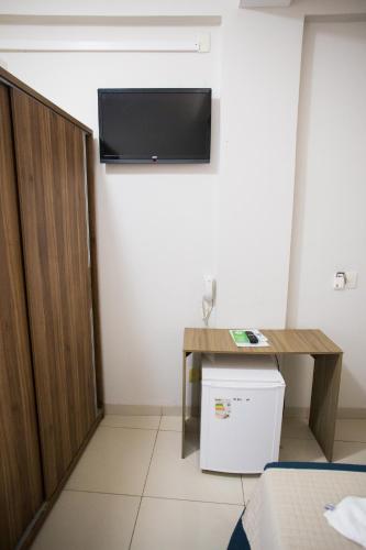 a room with a desk and a tv on the wall at Pousada Orla dos Corais in Maragogi